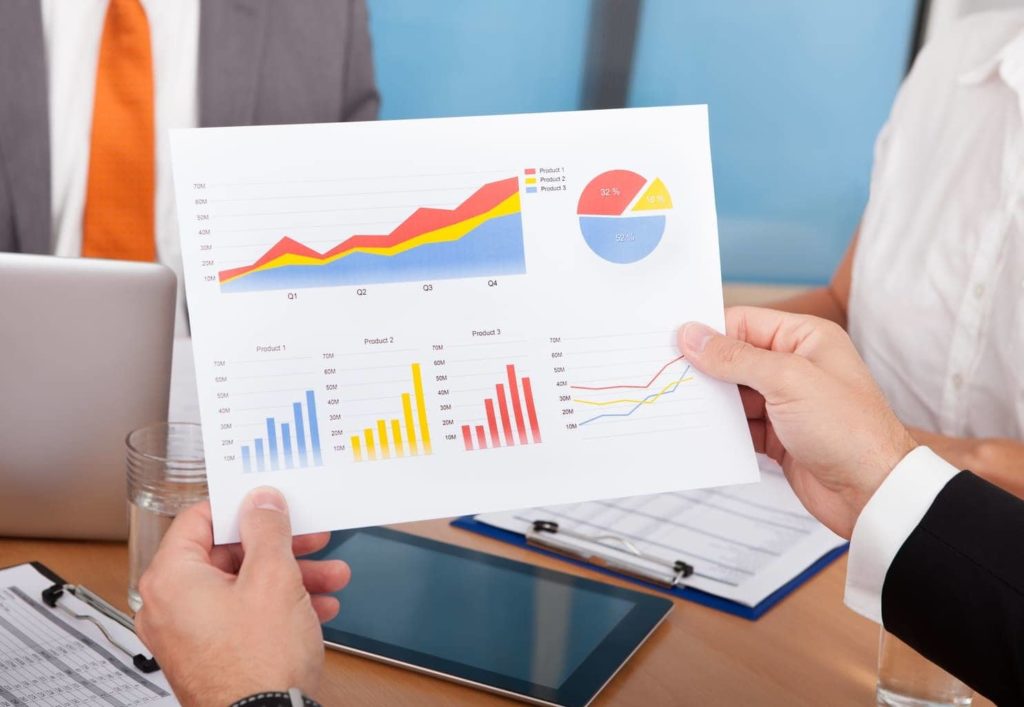 An example of measuring sales pipeline metrics -- a white man holding a printout containing charts and graphs.